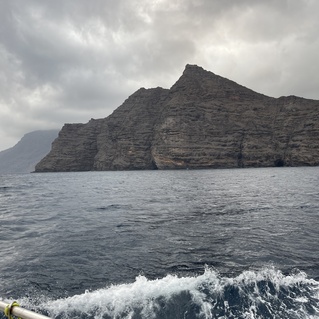 Felsen ragen vor einem bew&ouml;lkten Himmel aus dem Meer, Wellen schlagen sanft gegen die K&uuml;ste.