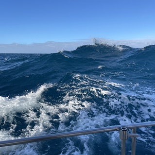 Dynamische Wellen brechen an der Oberfl&auml;che des tiefblauen Wassers unter einem klaren Himmel.