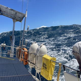 Blick von einem Segelboot auf hohe Wellen und aufgew&uuml;hltes Wasser unter klarem Himmel.