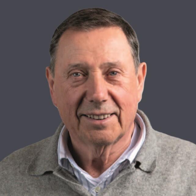 Portr&auml;t eines &auml;lteren Mannes mit kurzem, grauen Haar, in einem grauen Pullover vor einem grauen Hintergrund.